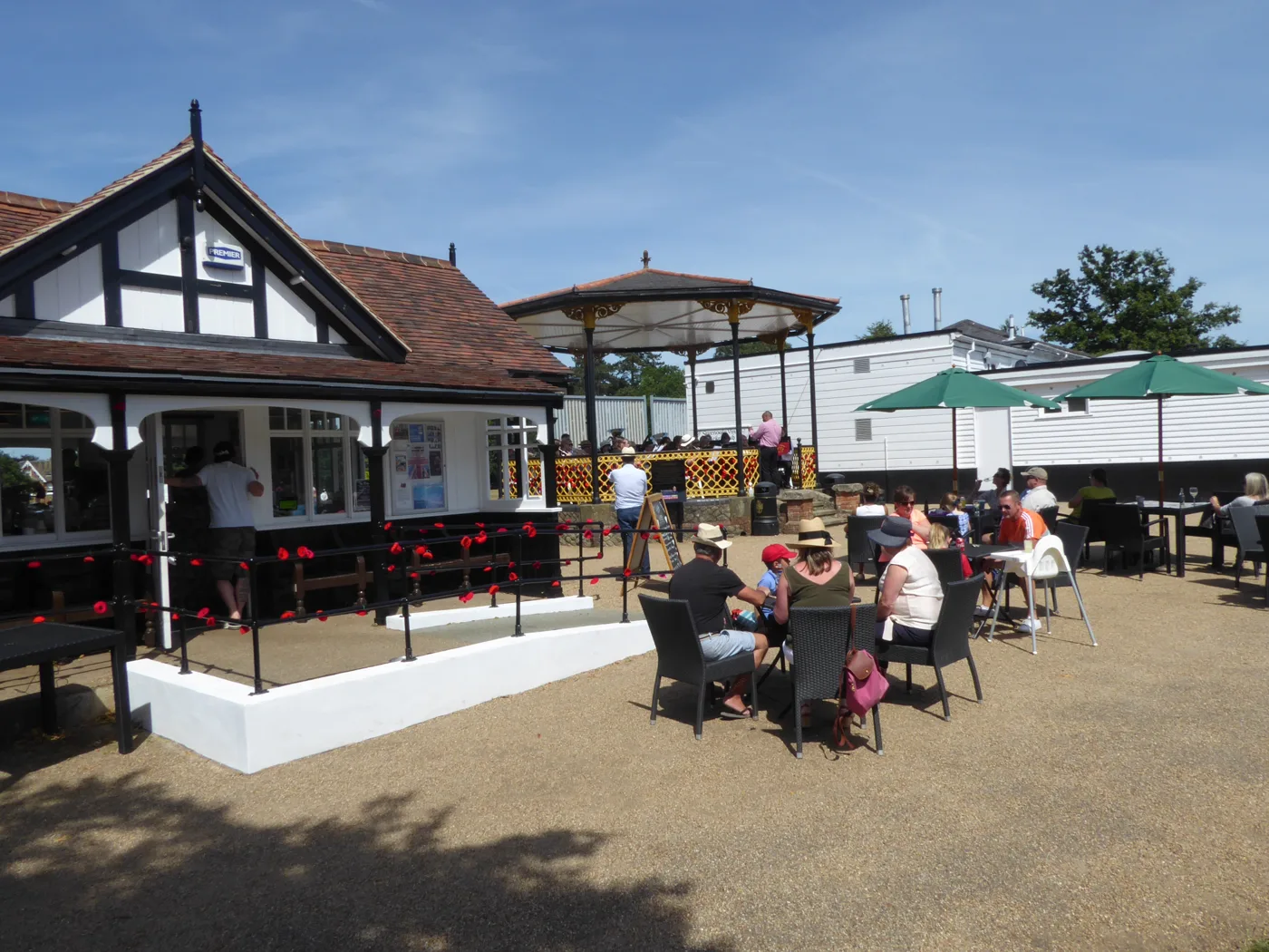 The pavilion on the Vine cricket ground, Sevenoaks, home of Cafe on the Vine, with its outside tables in use and the bandstand behind.