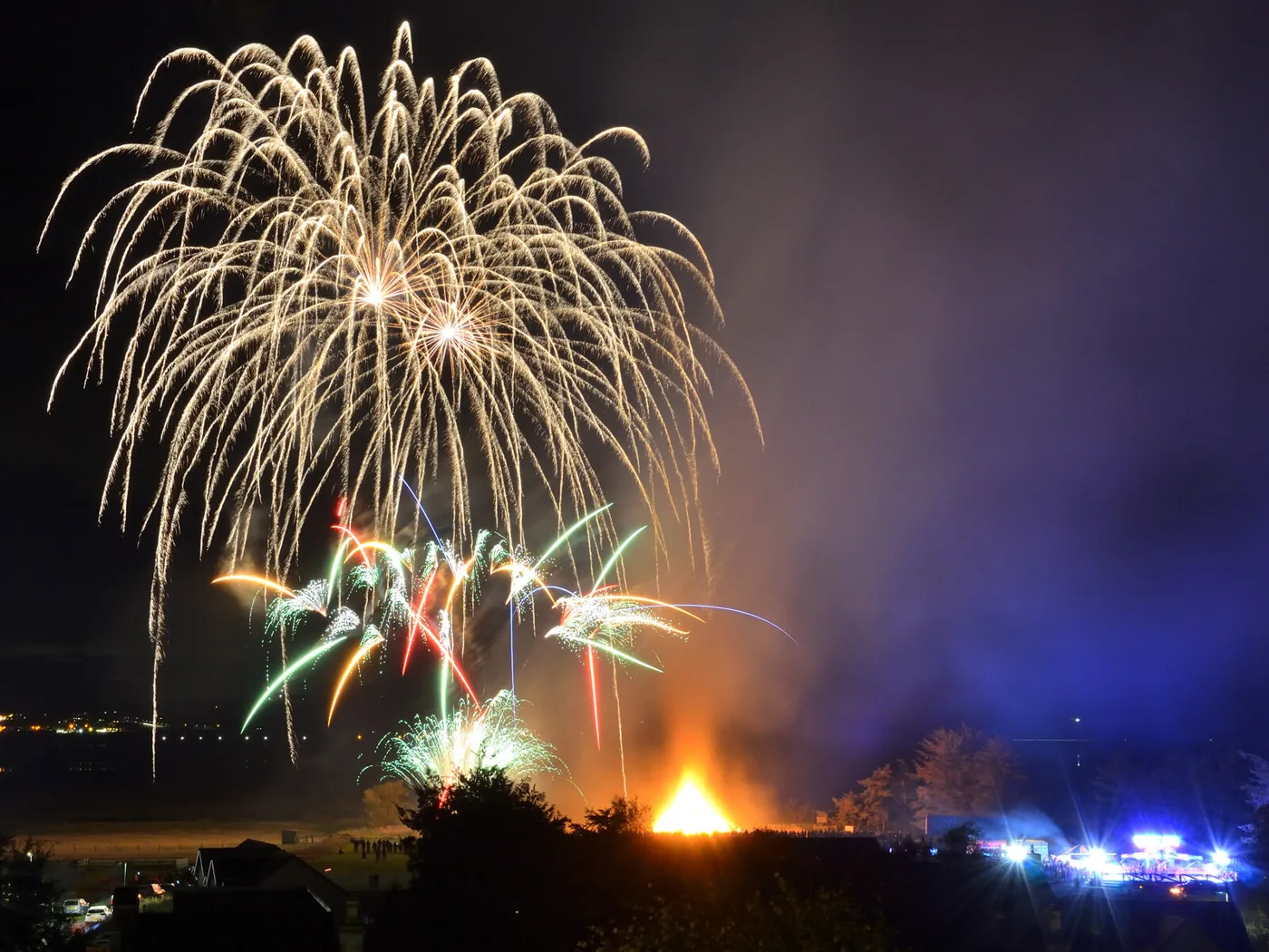 A community Bonfire Night display, with the bonfire alight below the fireworks. Photographed at Dornoch, not in Kent.