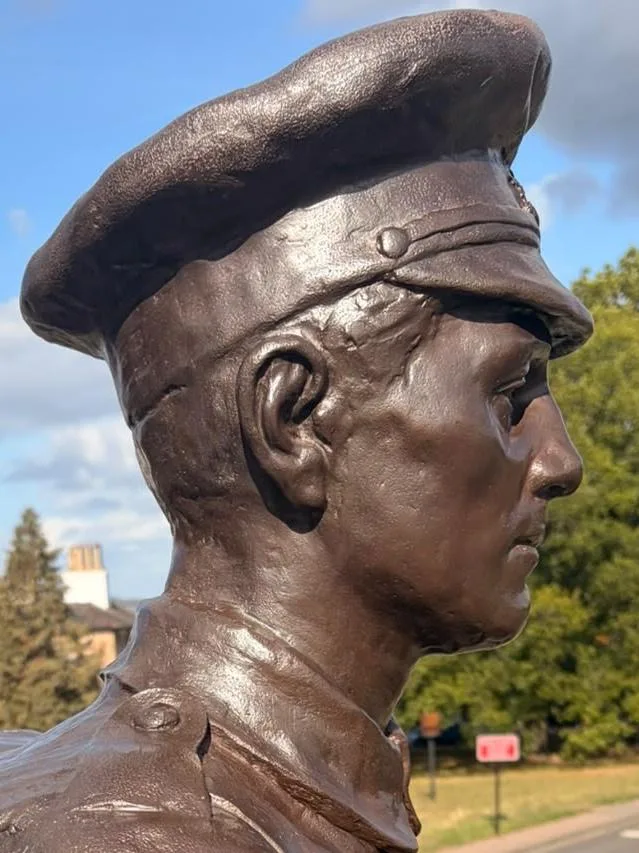 Side view of the soldier's head after treatment, a smooth even brown bronze showing the ear, cap peak and chinstrap button