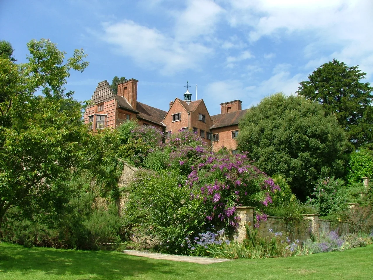 Chartwell house from the garden below, with the Kentish ragstone wall and the summer borders in front of the brick front.